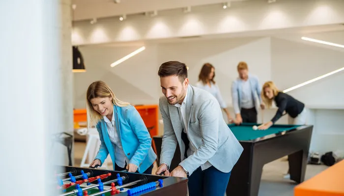 coworkers playing foosball billiards break room