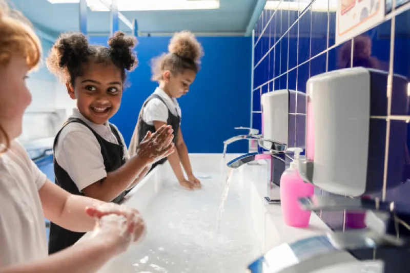students washing hands in school bathroom